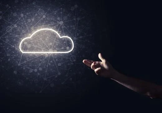 A person's hand pointing at a glowing white cloud symbol surrounded by digital network lines, dark background.