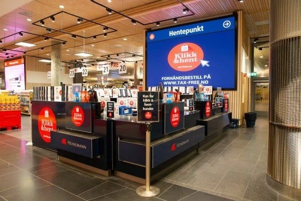 Hentepunkt tax-free Klikk & Hent pickup counters with branded digital display screen inside a Norwegian airport terminal.